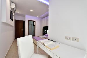 a white bedroom with a bed and a desk at B&B La Torre in Loceri