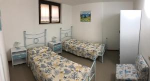 a room with two beds and two tables and a mirror at MARIA'S HOUSE in Porto Pino