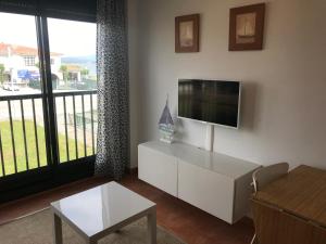sala de estar con TV de pantalla plana y sofá en Apartamento en la Isla en Isla de Arosa