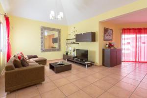 ein Wohnzimmer mit Sofa und Fernseher in der Unterkunft Villa Bella Lucia 1. Piscina Climatizada, WiFi, BBQ. in Corralejo