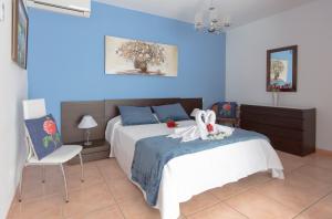 ein Schlafzimmer mit einem weißen Bett und einer blauen Wand in der Unterkunft Villa Bella Lucia 1. Piscina Climatizada, WiFi, BBQ. in Corralejo + 33 Fotos