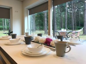 a table with white cups and saucers and flowers at Villa Männituka in Kirikuküla