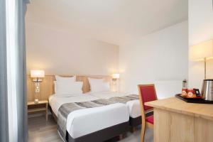 a hotel room with a large bed and a desk at Hôtel Le Compostelle in Paris