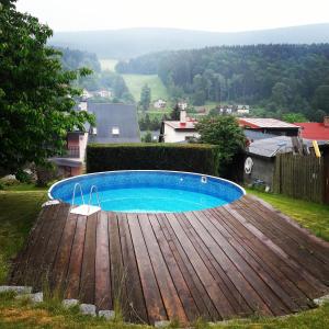 a swimming pool with a wooden deck around it at Vila Pramínek, Krkonoše s bazénem kousek od Pece pod Sněžkou in Horní Maršov +69 photos