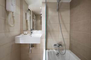 a bathroom with a shower, sink, and mirror at Hôtel Le Compostelle in Paris