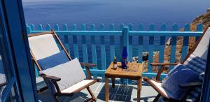 a balcony with two chairs and a table with wine bottles at Aegean Eye Apartments in Kastron