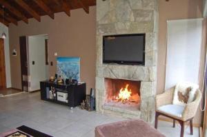 a living room with a fireplace with a flat screen tv at Orillas del Gutierrez in San Carlos de Bariloche