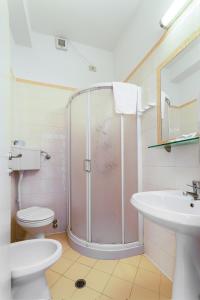 een badkamer met een douche, een toilet en een wastafel bij Hotel Stresa in Rimini