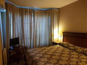 Habitación de hotel con cama y TV en Millenium Mendoza Apartments en Mendoza