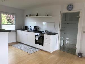 a kitchen with white cabinets and a clock on the wall at Ankerplatz Langballig in Langballig