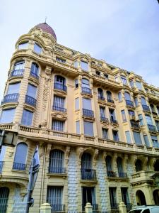 a large yellow building with windows and a flag at Palais Ophelia in Nice