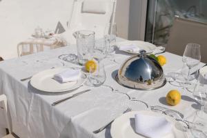 uma mesa com uma toalha de mesa branca com óculos e uma chaleira. em Gli Orti Di Malva B&B em Peschici