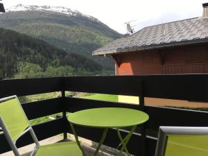 uma mesa verde e cadeiras numa varanda com uma montanha em Les Esserts em Les Houches