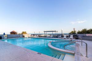 a large swimming pool with chairs and the ocean in the background at The Inn at Pine Knoll Shores in Pine Knoll Shores