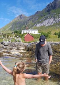 un hombre y una chica de pie en el agua en Solbakken en Ramberg