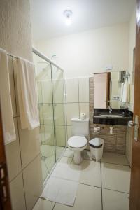 a bathroom with a toilet and a glass shower at Vila Dumont no Centro de Foz in Foz do Iguaçu