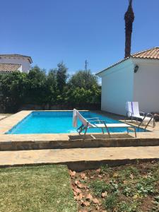 una piscina con 2 tumbonas junto a una casa en Villa Fructus en Vejer de la Frontera