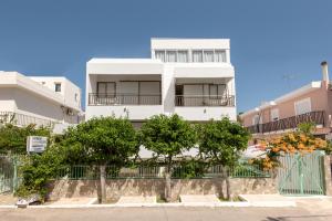 a white building with trees in front of it at Kardamena Holiday Apartments in Kardamaina