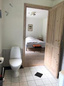 a bathroom with a toilet and a bed at Tranum Lys og Glas in Brovst