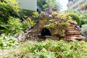 a stone fireplace in a garden with plants at Viva Victoria Guest House in Adler