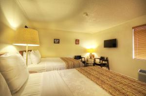 a hotel room with two beds and a television at Roadrunner Lodge Motel in Tucumcari