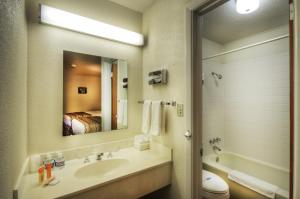 a bathroom with a sink and a mirror and a bed at Roadrunner Lodge Motel in Tucumcari