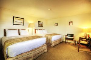 a hotel room with two beds and a desk at Roadrunner Lodge Motel in Tucumcari