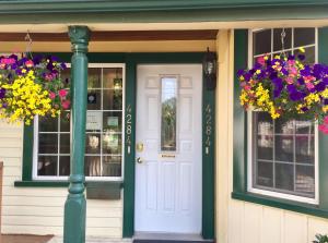 a house with a white door and two windows and flowers at Ellis House Bed & Breakfast in Niagara Falls