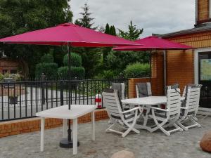 2 Tische und Stühle mit Sonnenschirmen auf einer Terrasse in der Unterkunft Ferienwohnung am Torbogen in Lübbenau