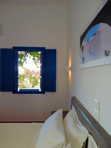 a bedroom with a bed and a window at Aegeo Hotel in Chora Folegandros