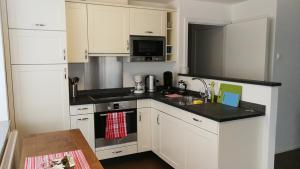 a kitchen with white cabinets and a black counter top at Holiday apartment #103 on Walensee in Unterterzen