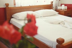 a bed with white sheets and a red flower in the foreground at Apartments Beti in Ulcinj