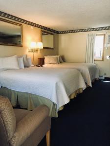um quarto de hotel com duas camas e uma cadeira em A Western Rose em Cody