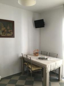 einen Esstisch mit Stühlen und einen TV an der Wand in der Unterkunft B&B Dimora Boemondo in Canosa di Puglia