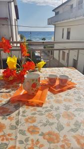 una mesa con 2 tazas y flores en el balcón en A Levante en Ascea