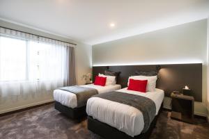 2 camas en una habitación de hotel con almohadas rojas en Kings On Peace, en Rotorua