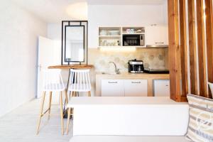 eine Küche mit weißen Schränken, einer Theke und Stühlen in der Unterkunft Sunrise Apartments in Agia Pelagia