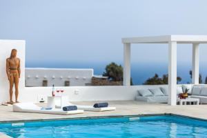 a woman in a bikini standing next to a swimming pool at Amazing Villa 6bed in Agios Lazaros Mykonos in Psarou