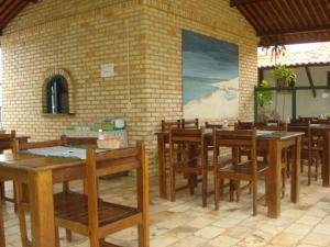 um restaurante com mesas e cadeiras de madeira e uma parede de tijolos em Pousada 7 Mares em Canoa Quebrada