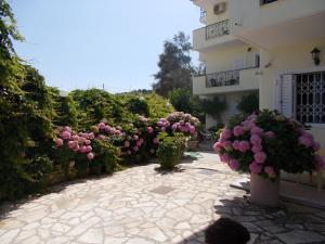 a courtyard with pink flowers and a building at Pansion Filoxenia Apartments & Studios in Tsoukalades