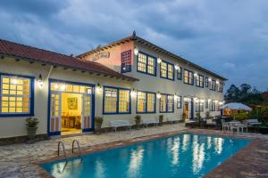 a villa with a swimming pool in front of a building at Pousada Berço da Liberdade in Tiradentes