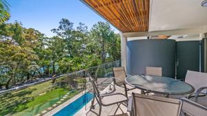 balcón con mesa, sillas y piscina en Park Cove Apartments, en Noosa Heads