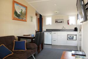 een keuken en een woonkamer met een bank en een tafel bij Manapouri Lakeview Motor Inn in Manapouri