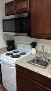 a kitchen with a stove and a sink and a microwave at Cattlemen Motel in Lovell