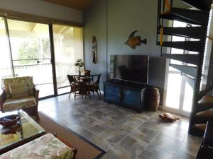 a living room with a television and a table with chairs at Turtle Bay Hale Lani Condo in Kahuku