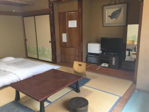 a room with a bed and a table and a tv at Daymaruya Ryokan in Yamanouchi