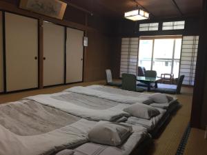 Daymaruya Ryokan في يامانوتشي: سريرين كبيرين في غرفة مع طاولة