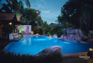 a large swimming pool with a rock in the middle at Tanjung Villa in Muar