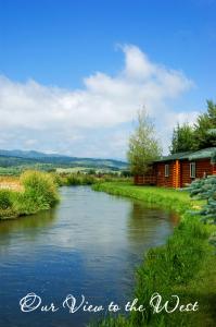 a river with a red house next to a building at Cabin Creek Inn in Thayne