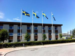 un grupo de banderas volando delante de un edificio en Optima Hotel Roslagen by Reikartz, en Norrtälje